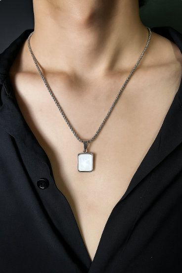 Necklace with a square pendant worn by a person against a black background