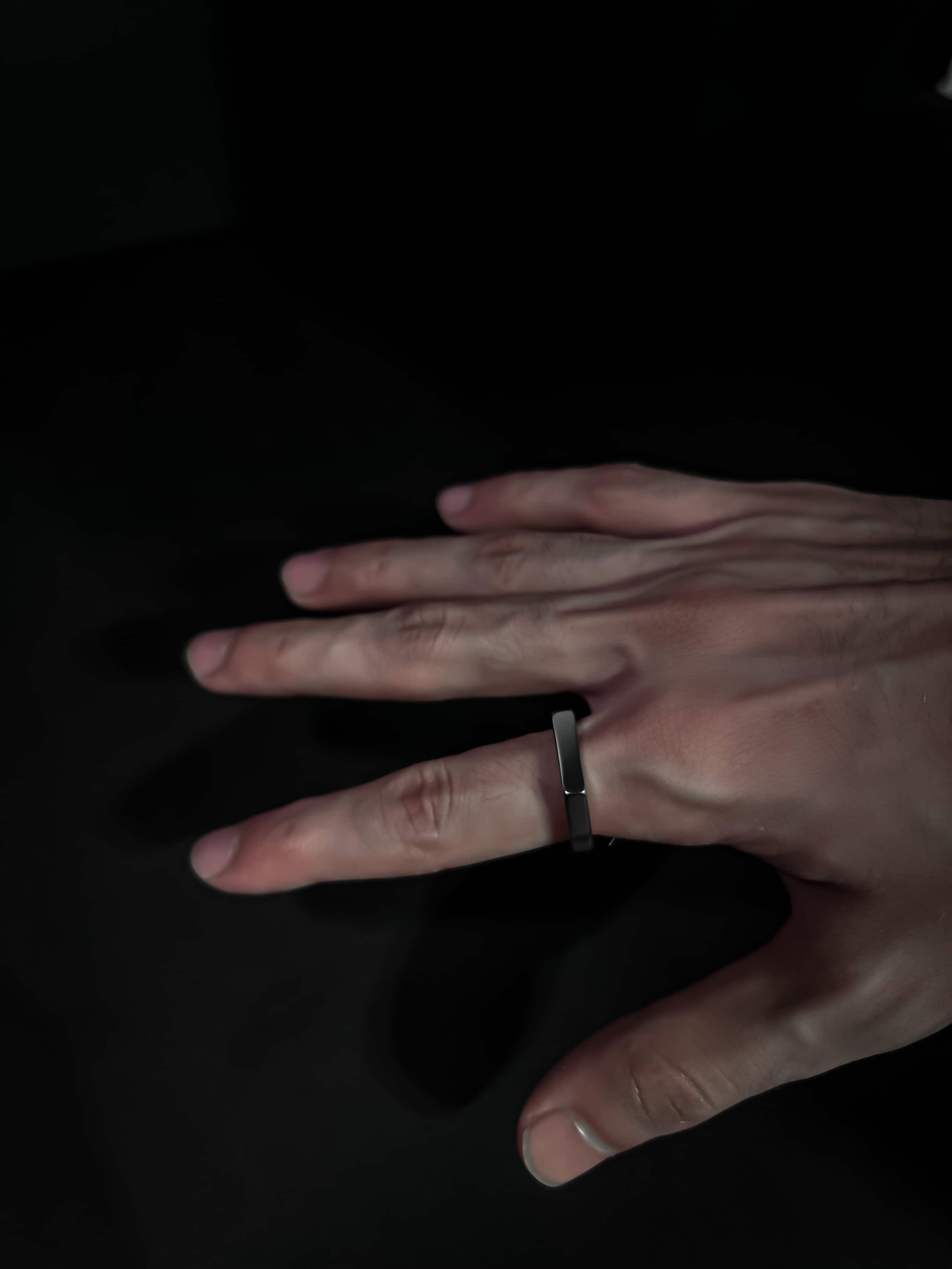 Hand wearing a ring on a black background