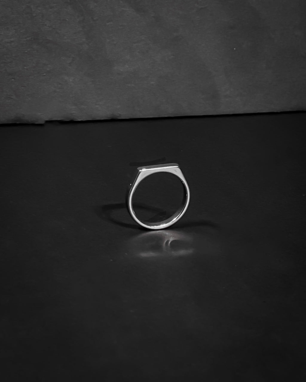 Silver ring on a dark reflective surface