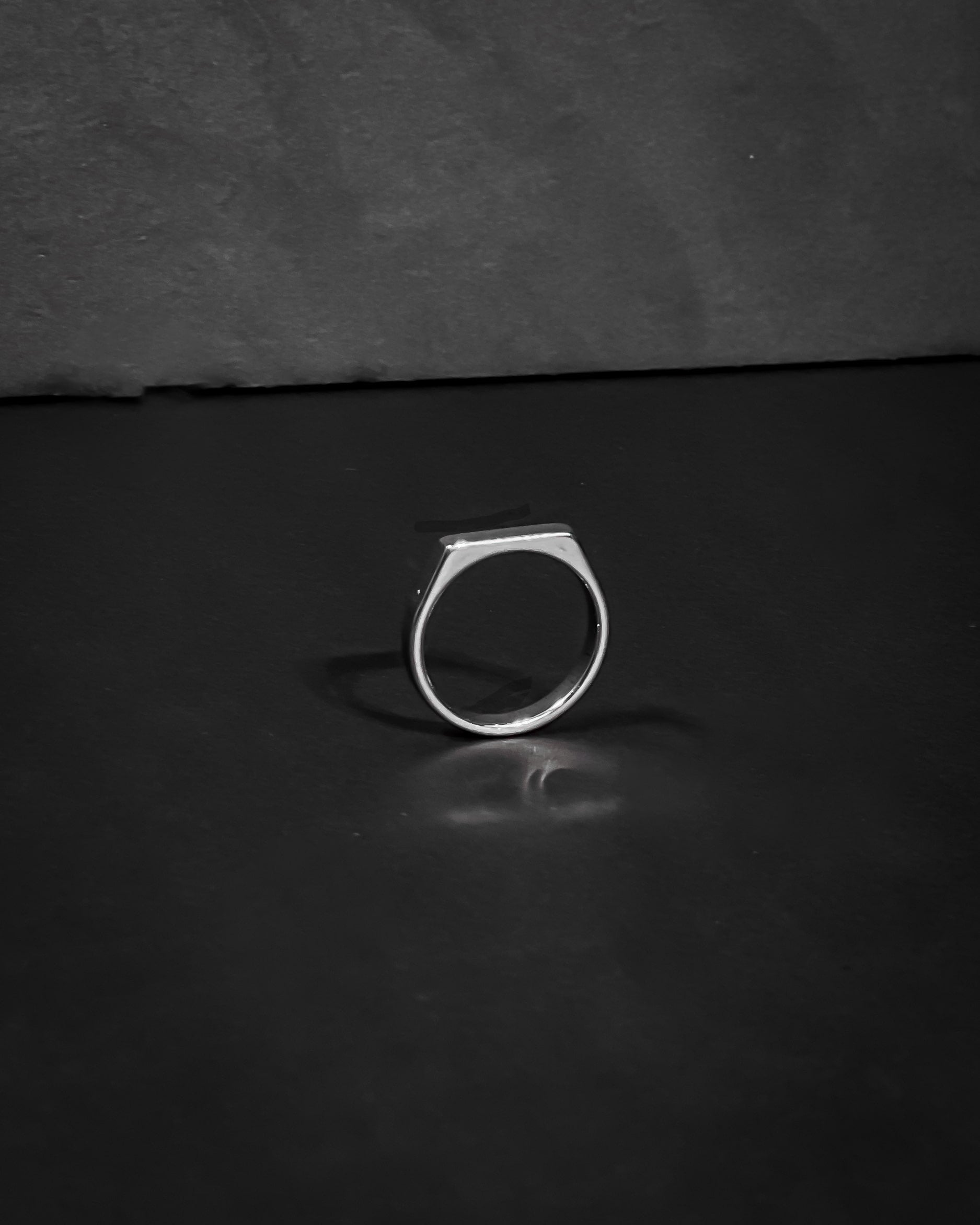 Silver ring on a dark reflective surface