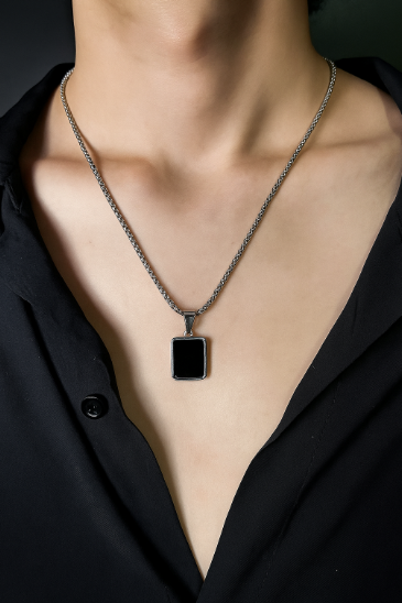 Person wearing a black pendant necklace with a plain background