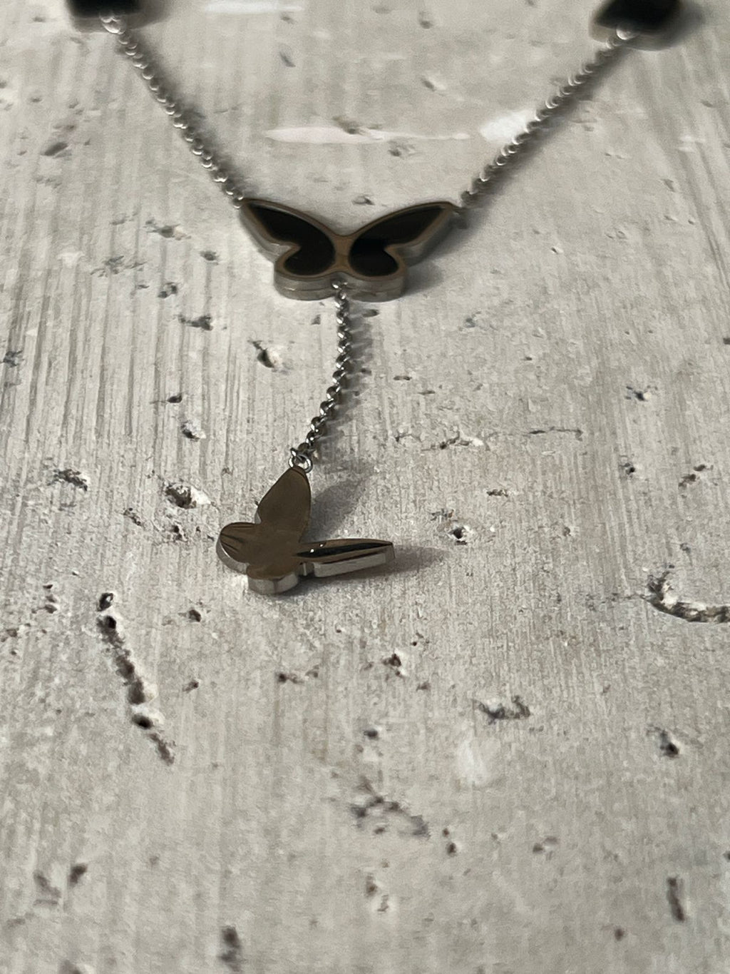 Butterfly pendant necklace with black charm accents — a piece of minimalist butterfly jewelry and nature-inspired design for everyday wear.
