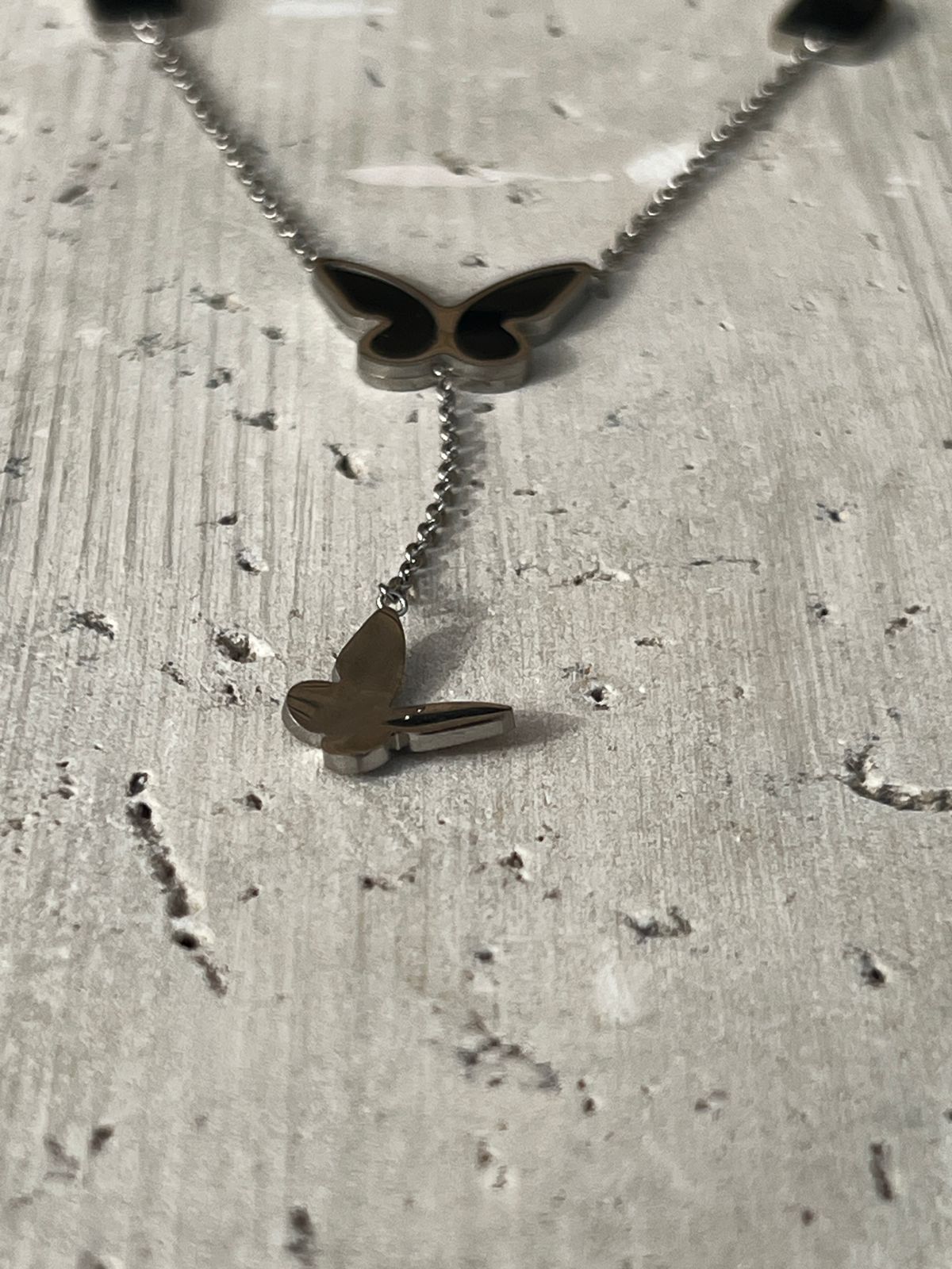 Butterfly pendant necklace with black charm accents — a piece of minimalist butterfly jewelry and nature-inspired design for everyday wear.