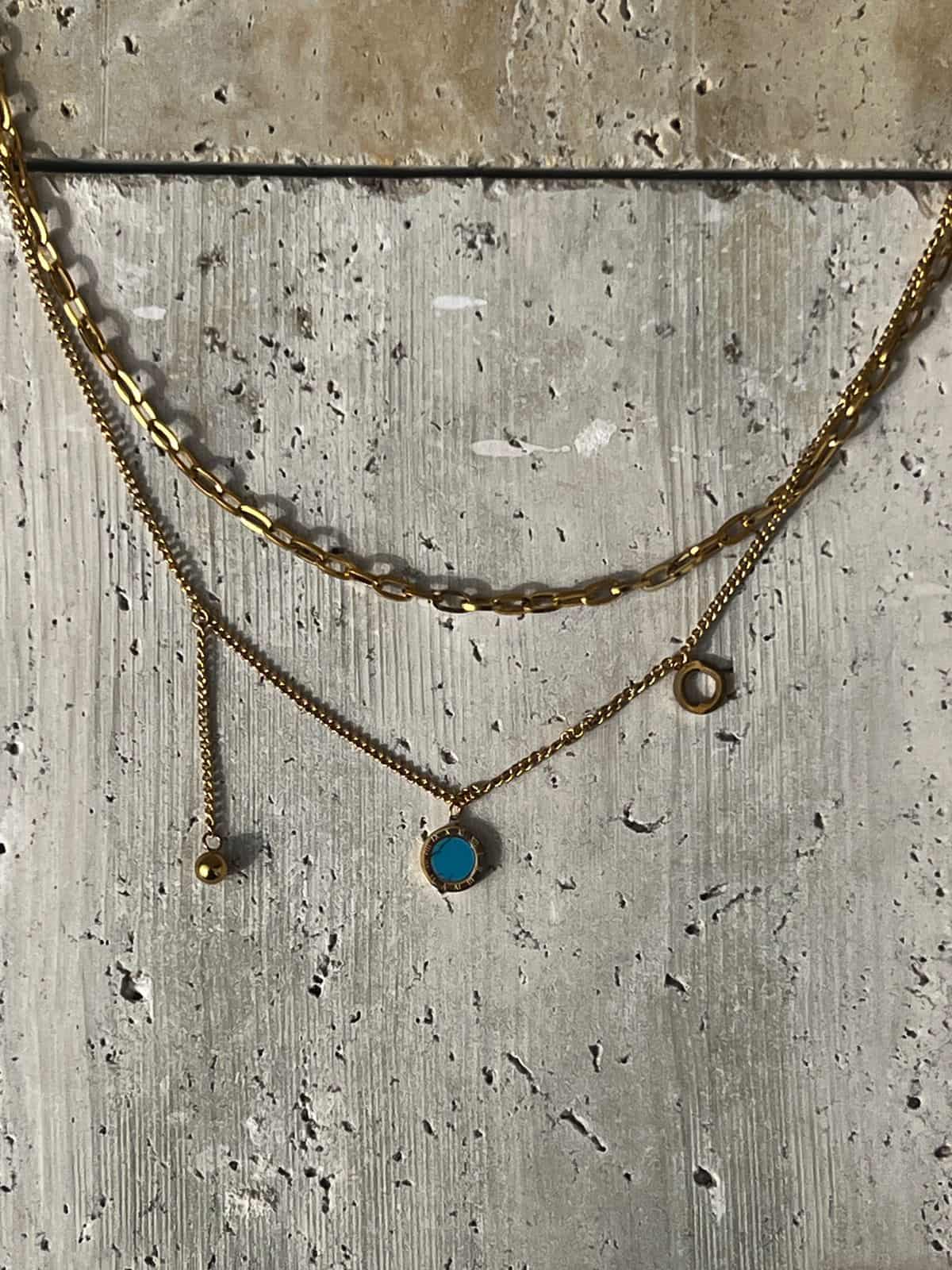 Layered gold necklace featuring a turquoise pendant — a piece of minimalist layered jewelry and an everyday statement necklace for women.
