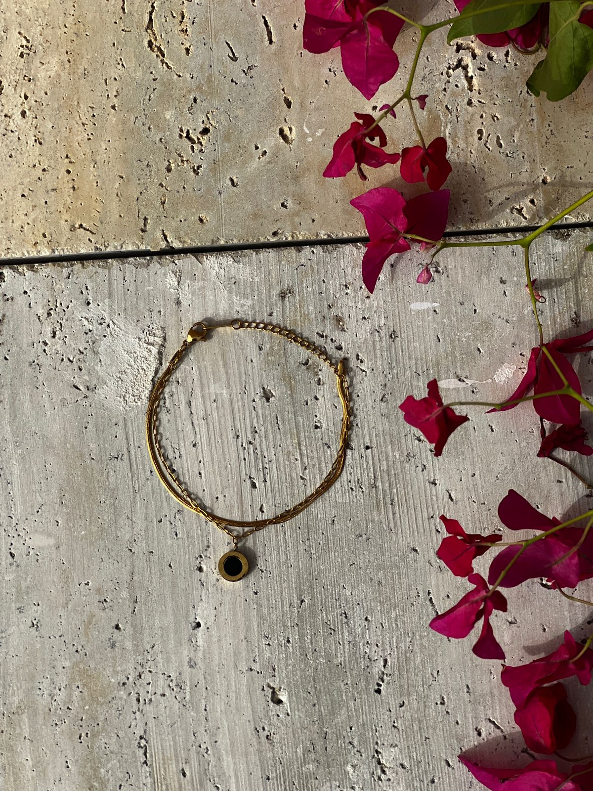 Black charm bracelet with a circular pendant on a minimalist gold chain — a modern fashion accessory and everyday wear bracelet for women.